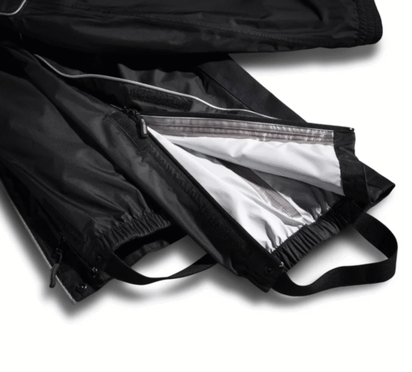 Pantaloni impermeabili neri aperti, interno grigio chiaro.